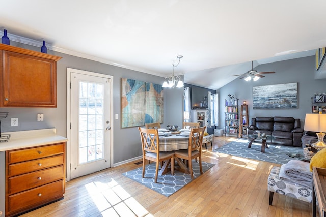 dining space featuring ornamental molding, lofted ceiling, ceiling fan with notable chandelier, and light wood-type flooring