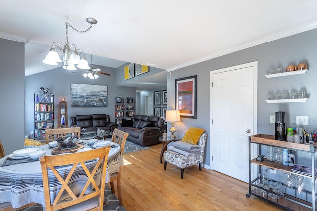 dining space with crown molding, lofted ceiling, wood-type flooring, and ceiling fan with notable chandelier