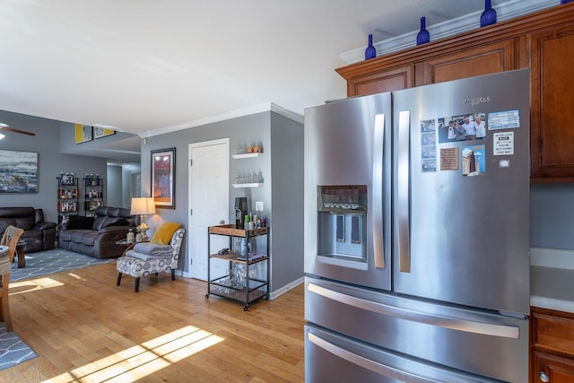 kitchen featuring stainless steel refrigerator with ice dispenser, ornamental molding, ceiling fan, and light wood-type flooring