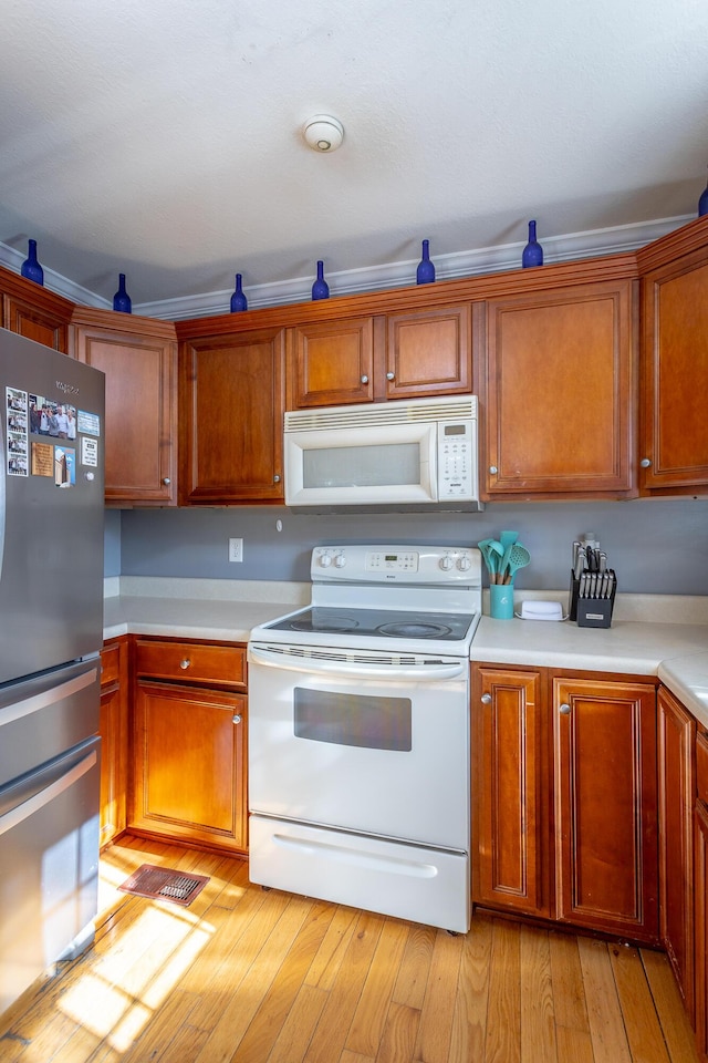 kitchen with white appliances and light hardwood / wood-style flooring