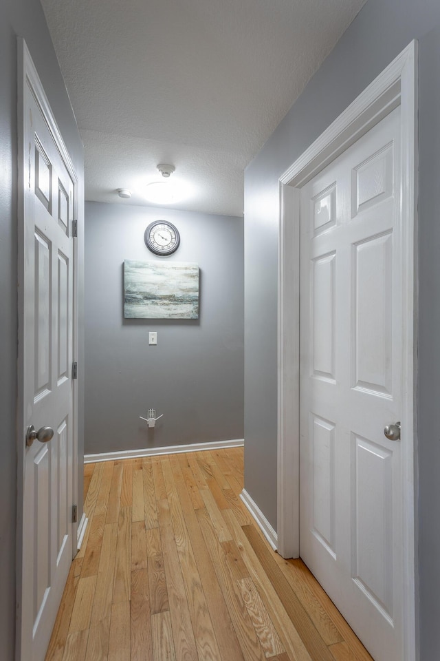 hall with light hardwood / wood-style floors and a textured ceiling