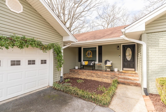 view of exterior entry with a porch and a garage