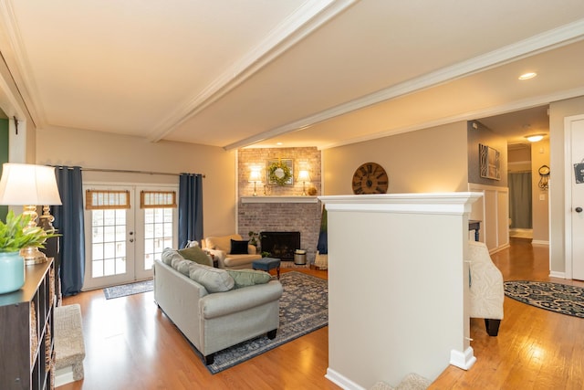 living room featuring french doors, crown molding, a brick fireplace, beam ceiling, and light hardwood / wood-style flooring