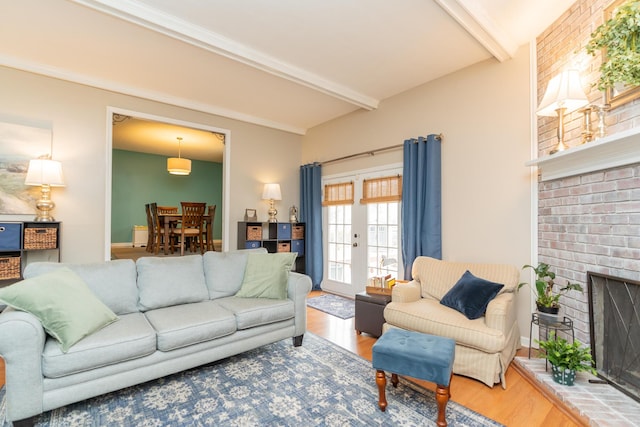 living room with beamed ceiling, a fireplace, hardwood / wood-style floors, and french doors