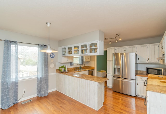 kitchen featuring stainless steel appliances, white cabinetry, hanging light fixtures, and sink