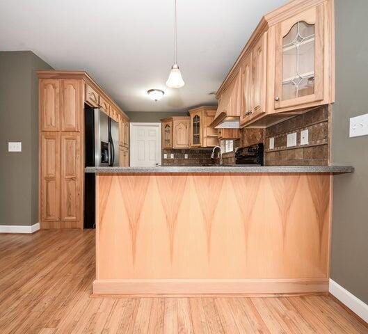 kitchen featuring stainless steel fridge with ice dispenser, backsplash, light hardwood / wood-style floors, and kitchen peninsula