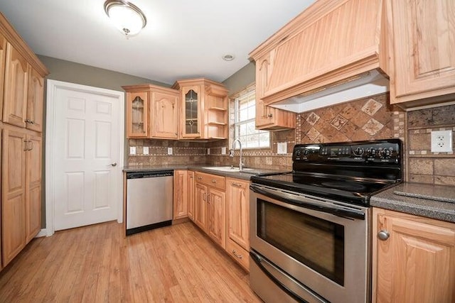 kitchen with sink, appliances with stainless steel finishes, light brown cabinets, custom range hood, and light wood-type flooring