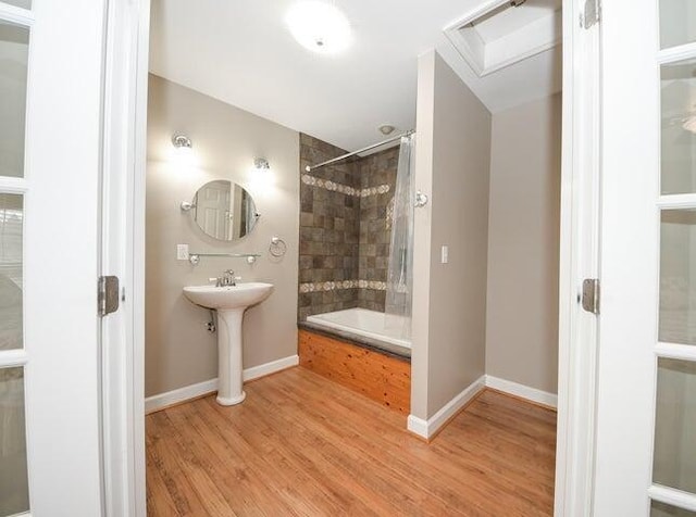 bathroom featuring sink, tiled shower / bath combo, and wood-type flooring