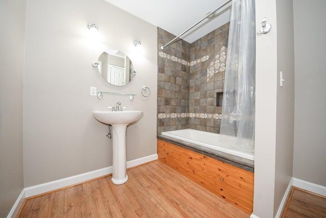 bathroom featuring tiled shower / bath combo and wood-type flooring