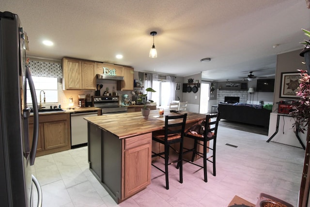 kitchen featuring butcher block counters, sink, decorative light fixtures, a center island, and appliances with stainless steel finishes