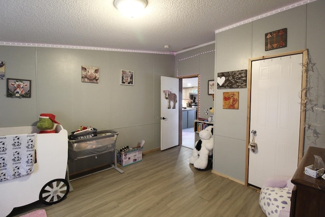 interior space with crown molding, wood-type flooring, and a textured ceiling