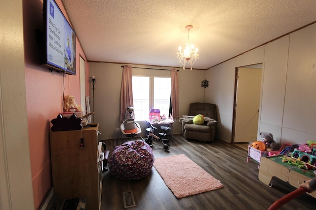 playroom with crown molding, a textured ceiling, a notable chandelier, and dark hardwood / wood-style flooring