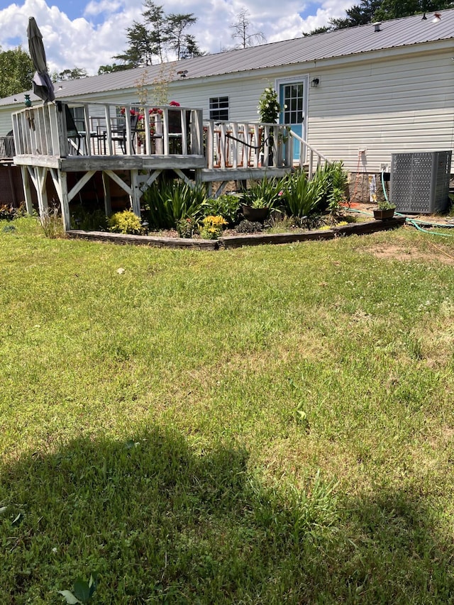 back of property with a wooden deck, a yard, and central AC