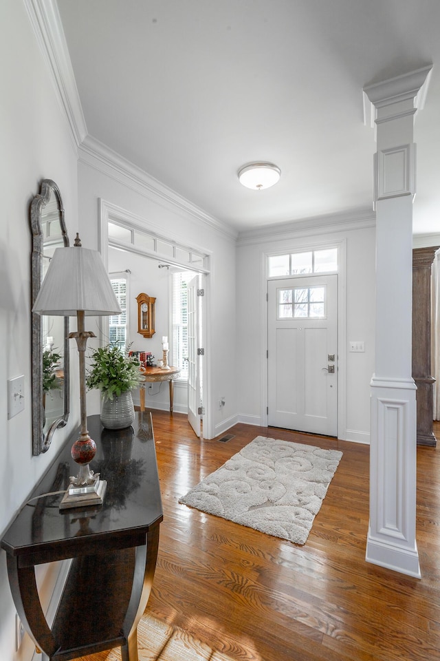 entrance foyer featuring a healthy amount of sunlight, ornamental molding, and ornate columns