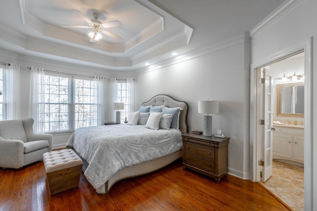 bedroom featuring ensuite bathroom, dark hardwood / wood-style floors, ornamental molding, ceiling fan, and a raised ceiling