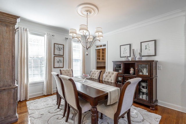 dining area with an inviting chandelier, ornamental molding, and dark hardwood / wood-style flooring