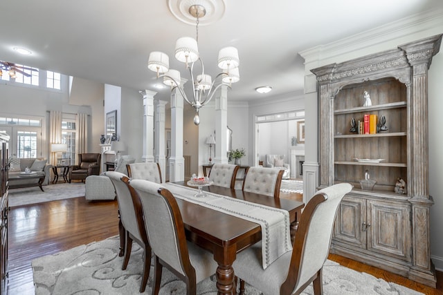 dining room featuring decorative columns, crown molding, hardwood / wood-style flooring, and a notable chandelier