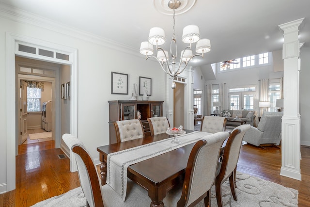 dining space featuring crown molding, dark wood-type flooring, washer / clothes dryer, a chandelier, and ornate columns