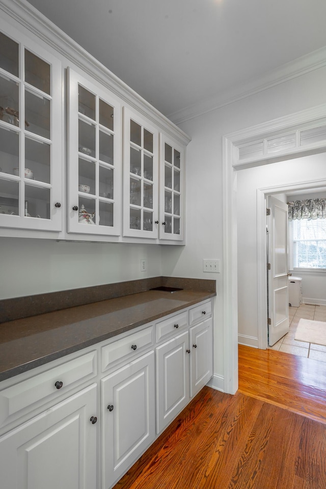 bar featuring hardwood / wood-style floors, crown molding, and white cabinets