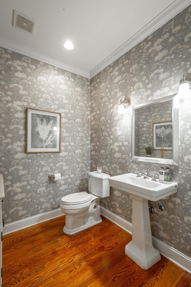 bathroom with hardwood / wood-style floors, crown molding, and toilet