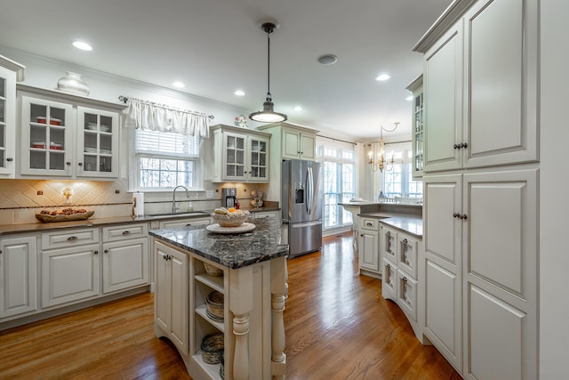 kitchen with a kitchen island, pendant lighting, white cabinets, stainless steel fridge, and light hardwood / wood-style flooring