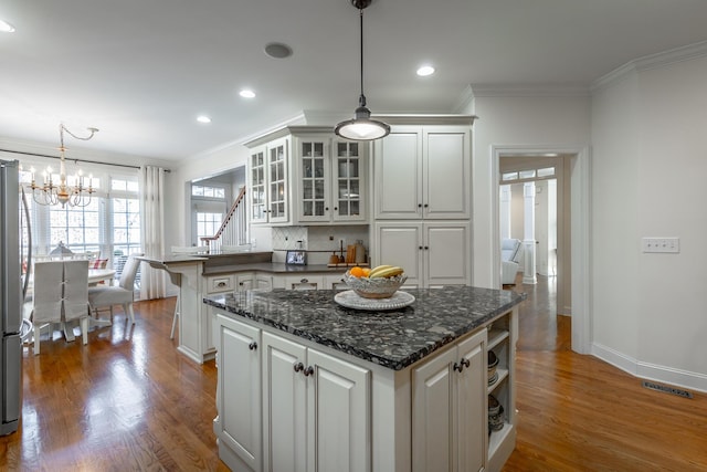 kitchen with white cabinetry, decorative light fixtures, dark wood-type flooring, and crown molding