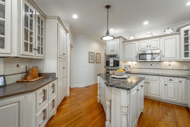 kitchen featuring crown molding, light hardwood / wood-style flooring, hanging light fixtures, stainless steel appliances, and white cabinets