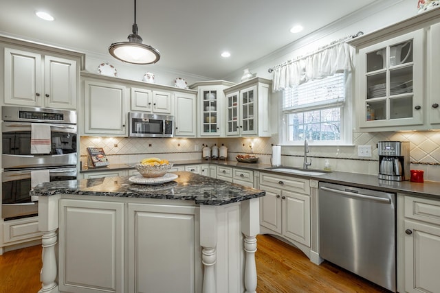 kitchen with stainless steel appliances, sink, pendant lighting, and light hardwood / wood-style flooring