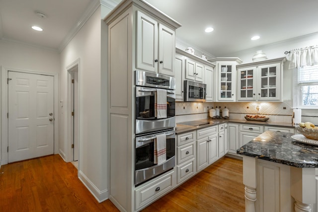 kitchen featuring stainless steel appliances, ornamental molding, hardwood / wood-style floors, and white cabinets