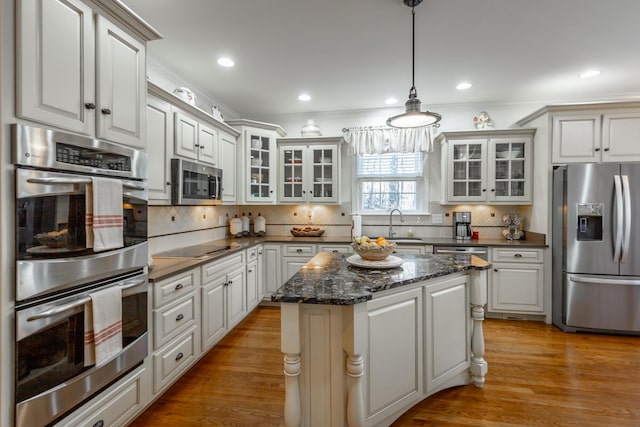 kitchen featuring hanging light fixtures, stainless steel appliances, light hardwood / wood-style floors, and white cabinets