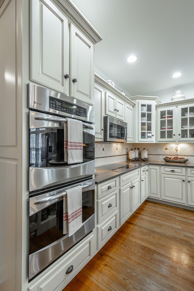 kitchen featuring white cabinetry, tasteful backsplash, stainless steel appliances, and light wood-type flooring