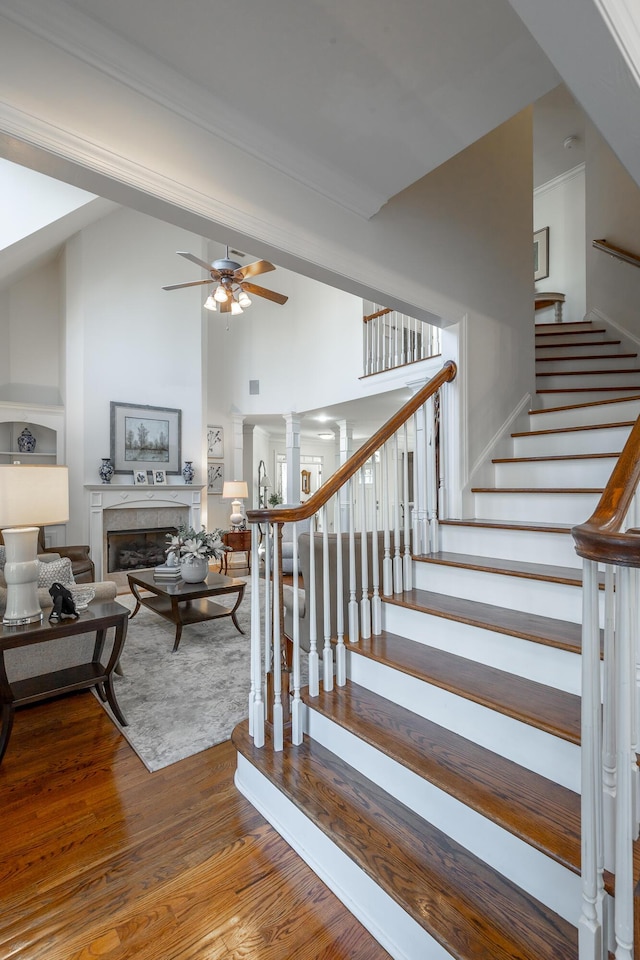 stairs with ornate columns, crown molding, high vaulted ceiling, hardwood / wood-style flooring, and ceiling fan