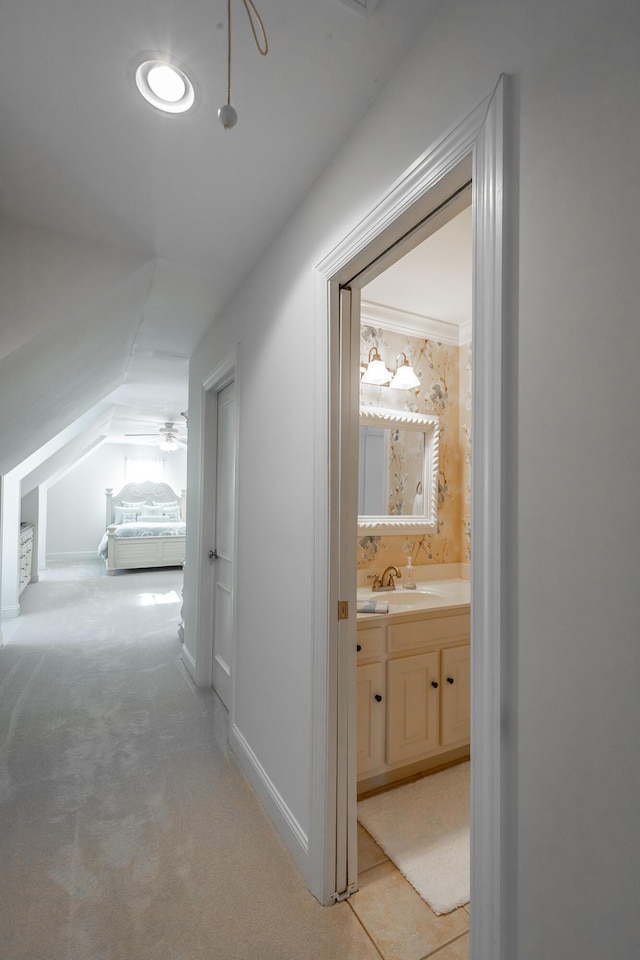 hall featuring light colored carpet, lofted ceiling, and sink