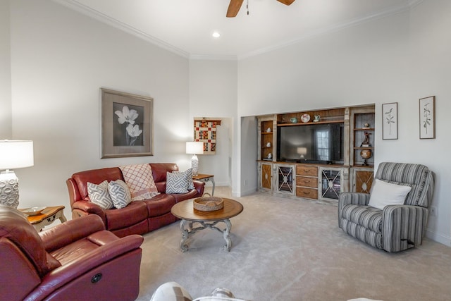 living room with a high ceiling, ornamental molding, light carpet, and ceiling fan