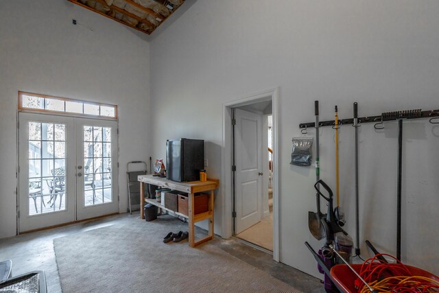 interior space with french doors, concrete floors, and a high ceiling