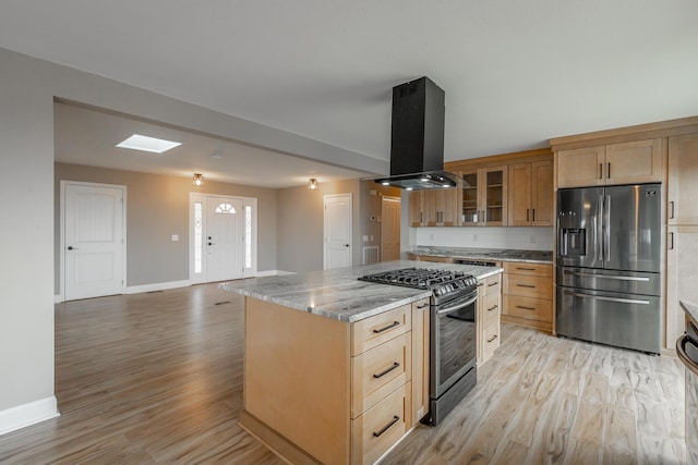 kitchen with appliances with stainless steel finishes, a kitchen island, island exhaust hood, light stone countertops, and light hardwood / wood-style flooring