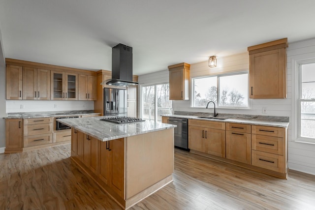 kitchen featuring appliances with stainless steel finishes, sink, island exhaust hood, a center island, and light hardwood / wood-style flooring