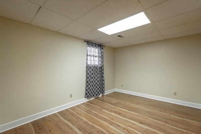 unfurnished room featuring hardwood / wood-style floors and a drop ceiling