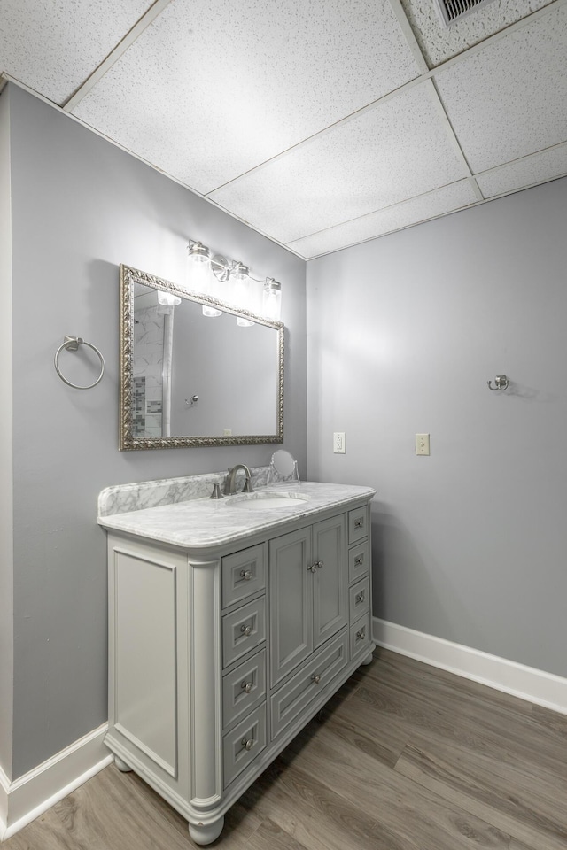 bathroom with vanity, hardwood / wood-style floors, and a drop ceiling