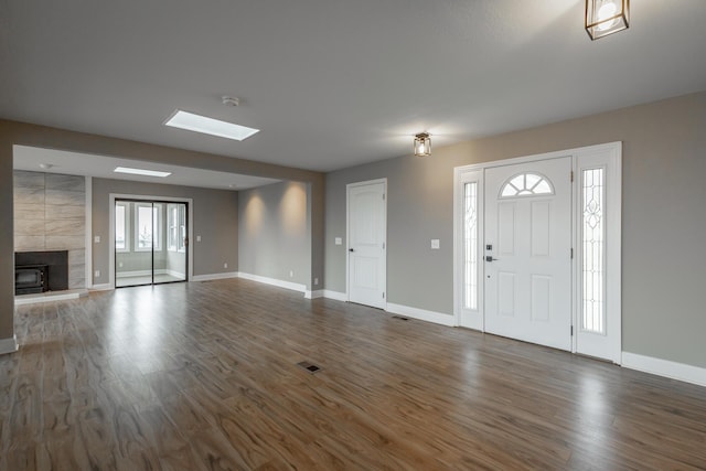 entryway featuring a tile fireplace, dark hardwood / wood-style floors, and a skylight