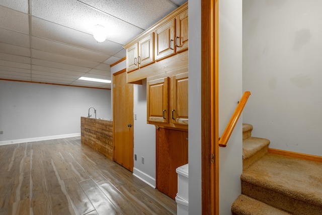 interior space with hardwood / wood-style floors, a paneled ceiling, and light brown cabinets