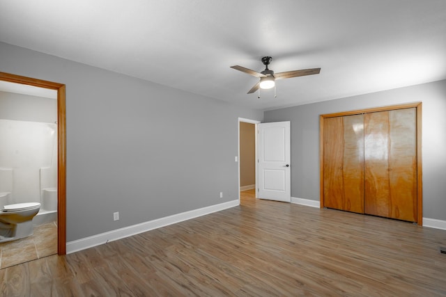 unfurnished bedroom with hardwood / wood-style flooring, ensuite bath, ceiling fan, and a closet