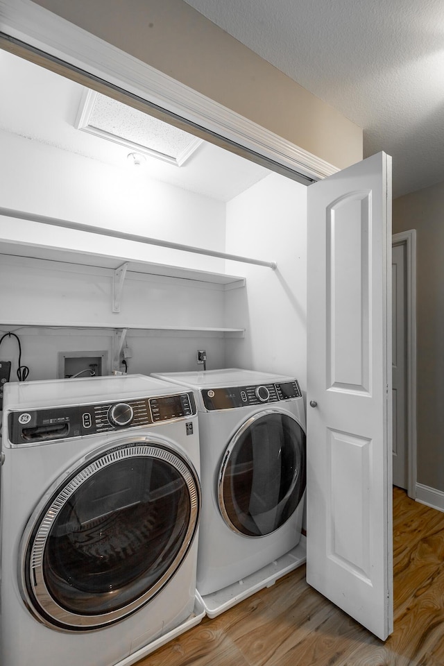 laundry area featuring hardwood / wood-style flooring, a textured ceiling, and washing machine and clothes dryer