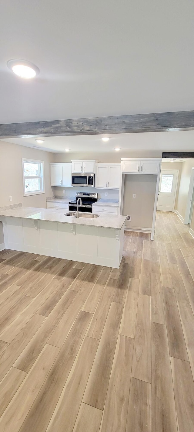 kitchen with white cabinetry, light stone counters, beam ceiling, and light hardwood / wood-style flooring