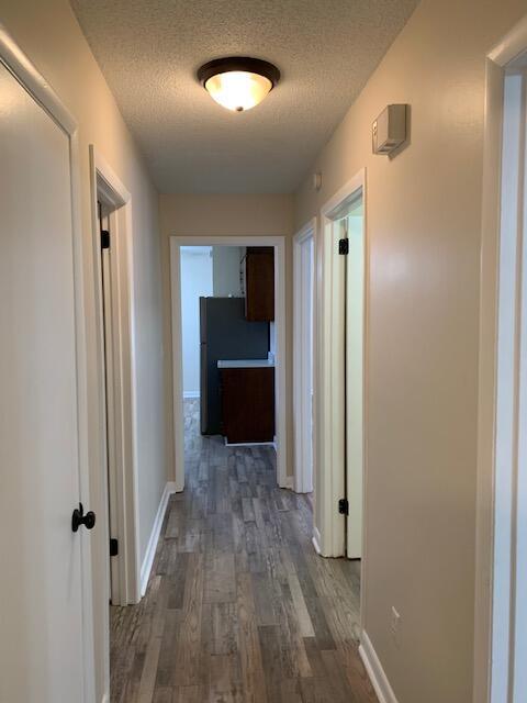 hall featuring dark hardwood / wood-style flooring and a textured ceiling