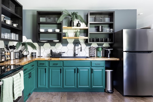 kitchen featuring hardwood / wood-style floors, wood counters, sink, backsplash, and stainless steel appliances