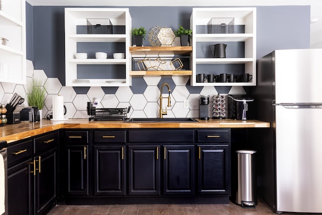 bar with tasteful backsplash, butcher block countertops, sink, and stainless steel refrigerator