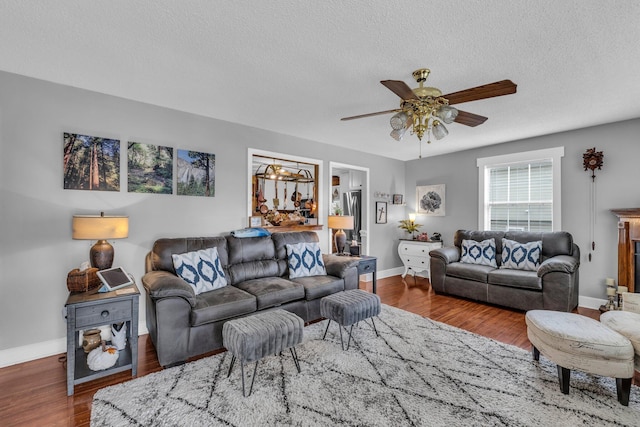 living room featuring ceiling fan, dark wood-type flooring, and a textured ceiling