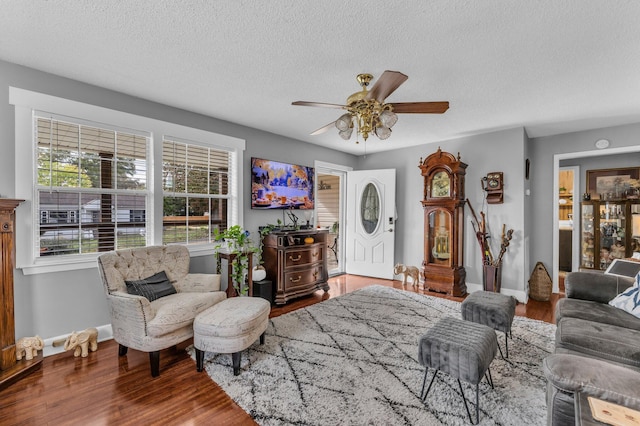 living room with ceiling fan, wood-type flooring, and a textured ceiling