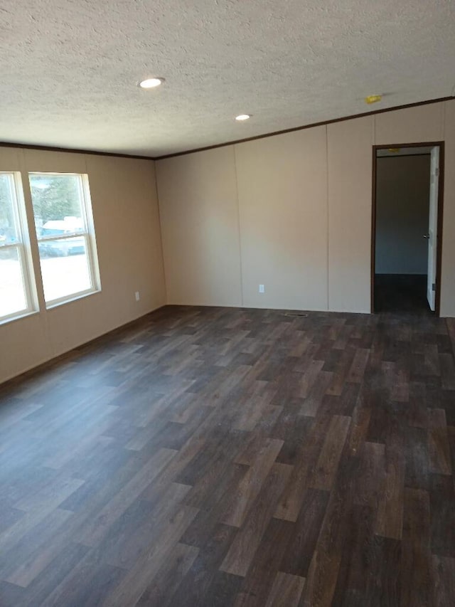 spare room with dark hardwood / wood-style floors and a textured ceiling